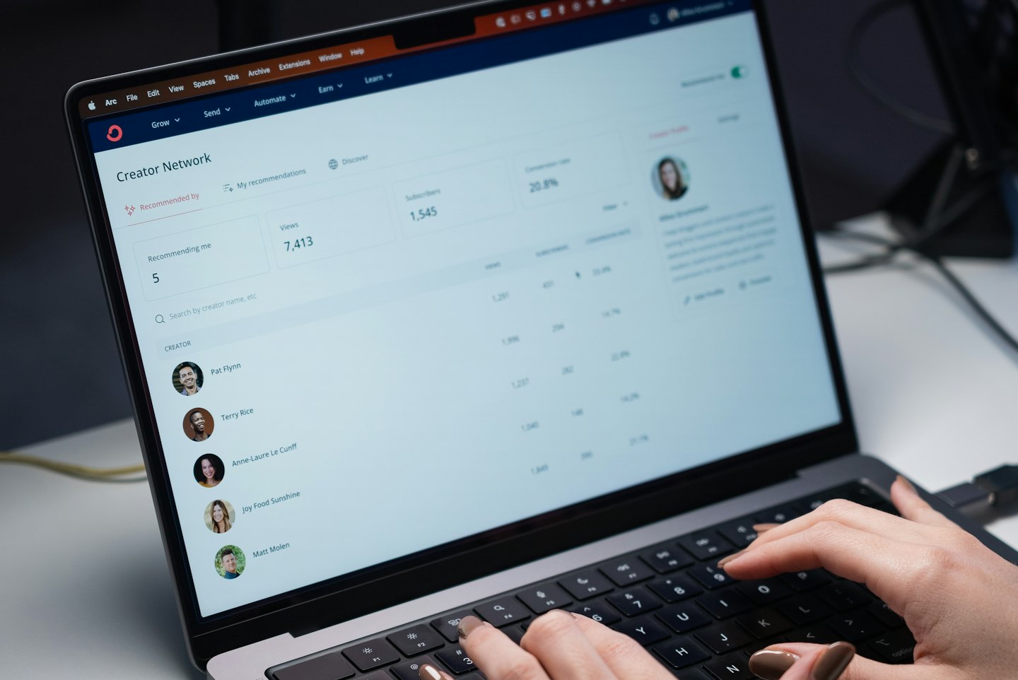 Hands typing on a laptop showing a creator network dashboard.